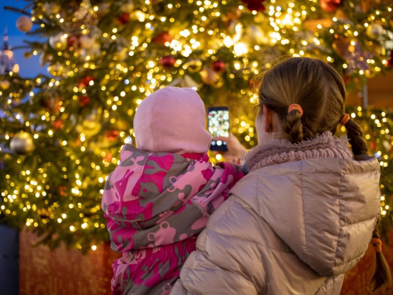 mom and baby in her arms photographing a Christmas tree in denver