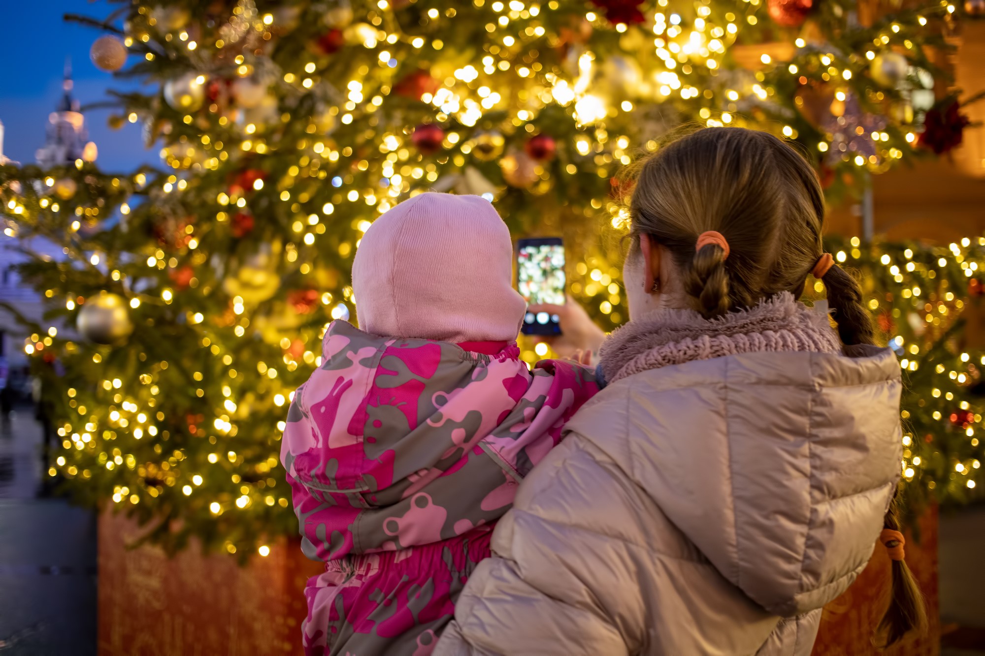 mom and baby in her arms photographing a Christmas tree in denver